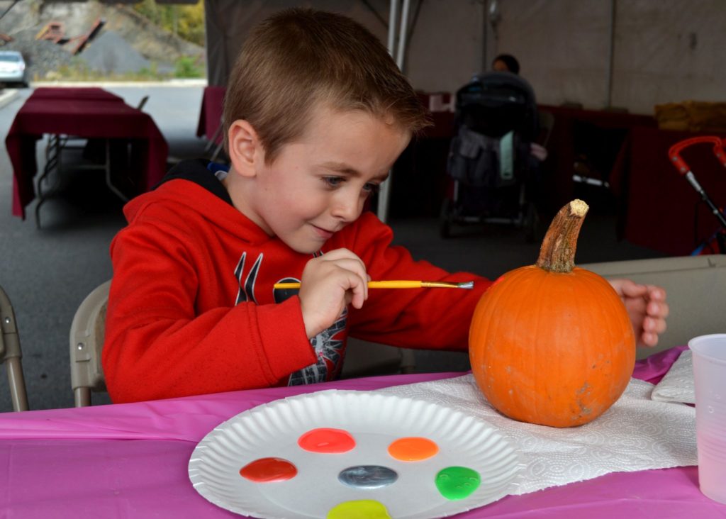 Community member, Alex Spangenberg, paints a pumpkin at the arts and crafts table