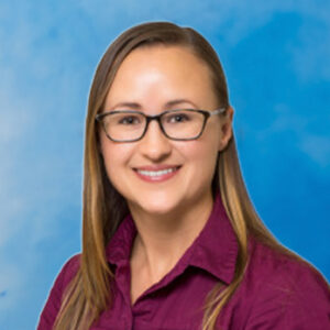 Amber's smiling headshot on blue background with long hair and glasses