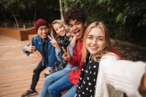 Grupo de alegres amigos adolescentes multiétnicos que se divierten juntos al aire libre, tomándose un selfie