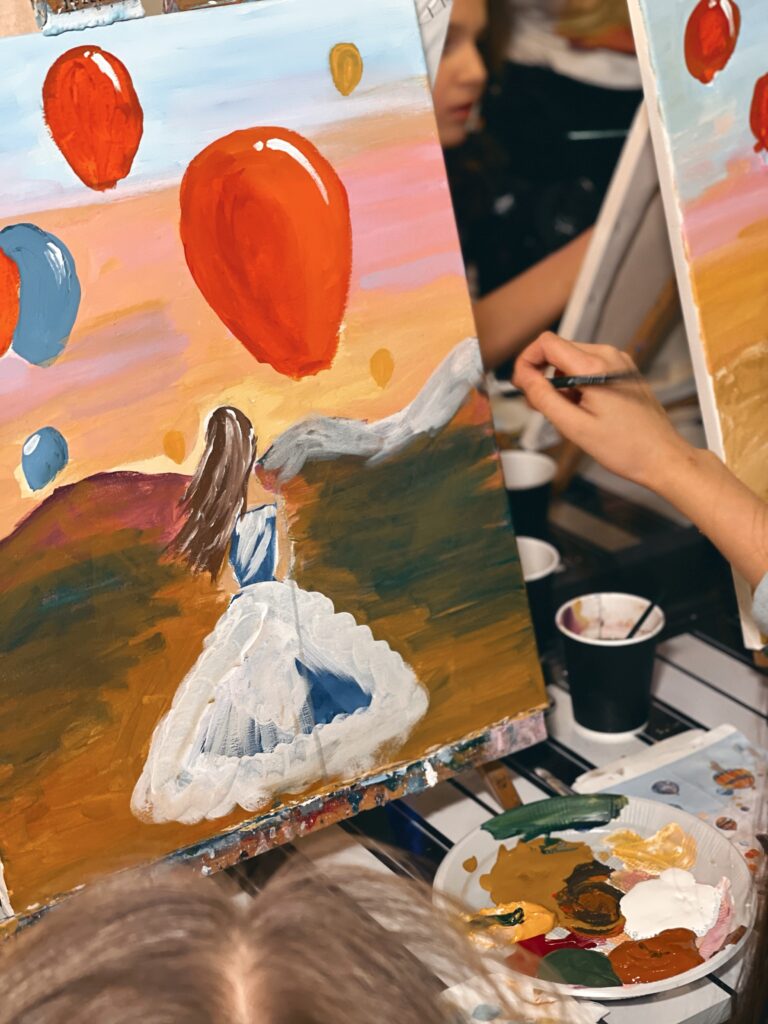 Picture of a painting of a girl in a white dress staring at the red balloon