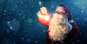 Feliz Papá Noel sosteniendo una bola de Navidad brillante sobre fondo azul desenfocado con espacio de copia