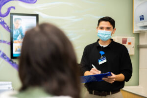 Nick Sardo, a community health worker at The Wright Center for Community Health Mid Valley Practice, takes notes while talking to a patient during a recent visit.