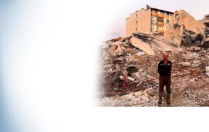 photo of a man standing before the ruins of a building in the Hatay Province of Turkey