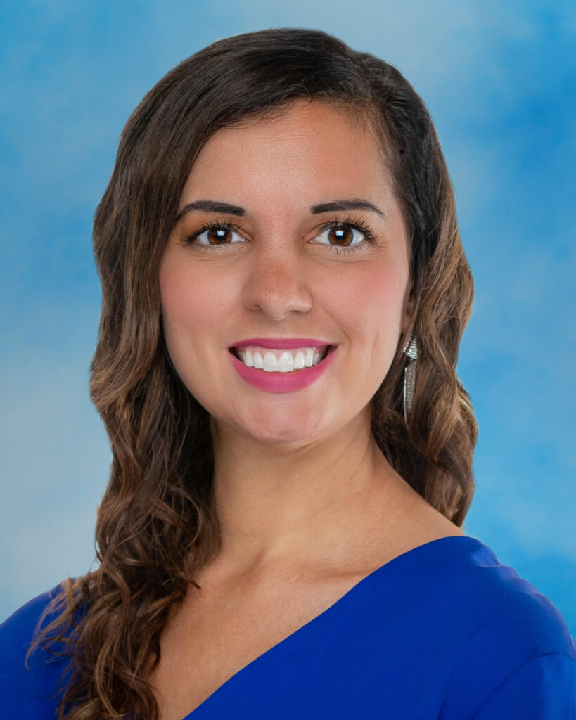 Melissa Germano-Ryczak smiling headshot on blue background with brown hair