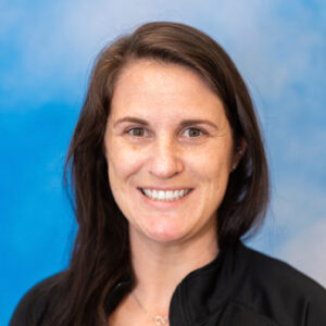Caroline's smiling headshot with long brown hair and black top