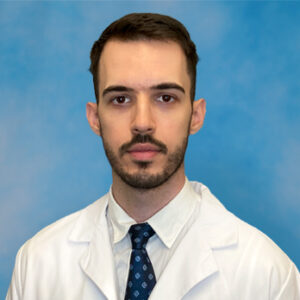 Predrag's headshot in white coat and dark facial hair and blue tie