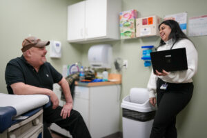 Patient in hat with a medical resident in a patient room interacting