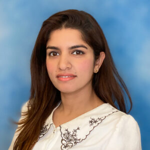 Dr Hassan's headshot with blue background and long dark hair