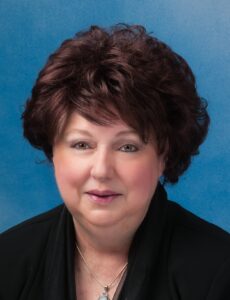 Mary's smiling headshot with short brown hair and blue background