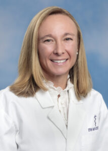 Erin's smiling headshot with blue background and white coat