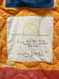 Dr. Pancoast's AIDS quilt square on orange blanket with a sunrise on the patch