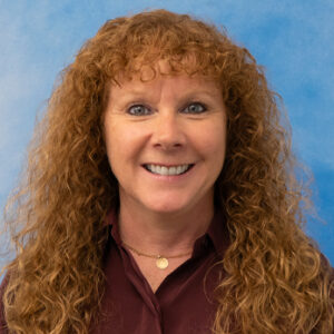 Lisa's smiling headshot with maroon top and long curly red hair