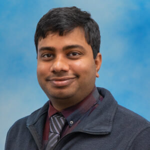 Dr. Maheswara Reddy Koppula's smiling headshot with dark top and tie