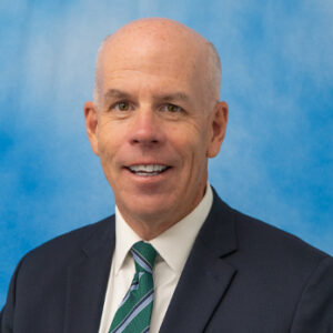 Mike's headshot with blue background and dark suit jacket