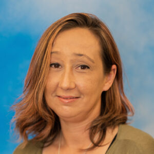 Nicole's headshot with blue background and green top