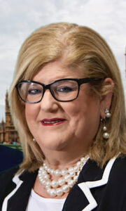 Rhonda's headshot with blond hair and black glasses and pearl necklace