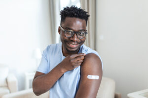 A man smiling while showing his arm after vaccine shot