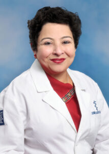 Portrait of Jumee Barooah smiling in white coat and red top