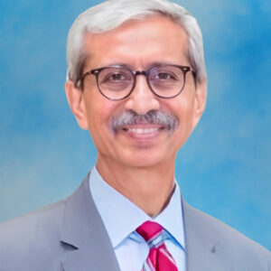 Headshot of board member Nasruddin Rupani smiling with glasses and grey suit and red striped tie