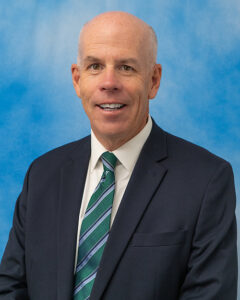 Headshot of Michael Mahon in dark suit and green striped tie