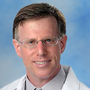 Dr Terry Buch's headshot smiling with glasses and white coat