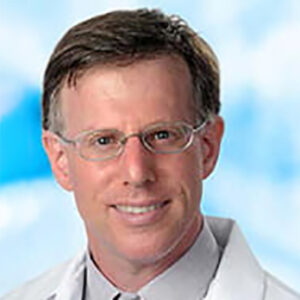 Dr Terry Buch's headshot smiling with glasses and white coat