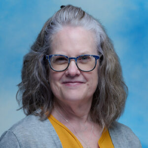 Headshot of Betsy Miller wearing glasses and grey top