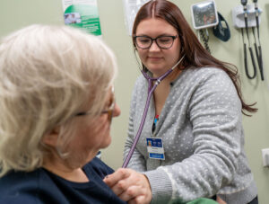 Isabella Watson, certified physician assistant, uses a stethoscope on a patient