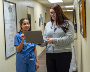 Isabella Watson, certified physician assistant, talks with a medical assistant as they are referring to a laptop screen