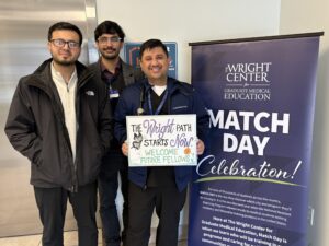 three resident physicians are standing next to a match day banner and they are holding a sign that says The Wright Path starts now. Welcome Fellows