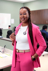 Amatus Legbedion standing in clinic setting in pink suit with stethoscope around her neck