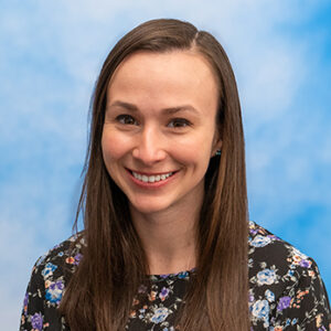 Brianna Galvin-Bayo's smiling headshot with long brown straight hair and floral top