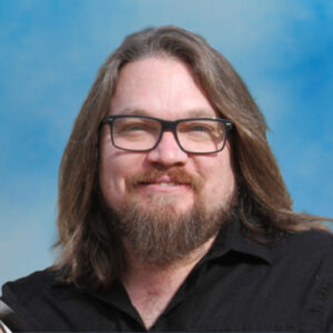 Bryan Stevenson headshot with long brown hair and beard and glasses