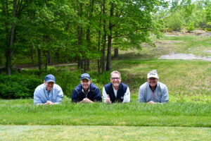 2025 William Waters Golf Tournament photo of 4 men laying in the grass