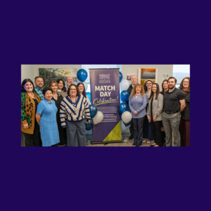 Photo of our gme staff standing in front of a match day banner