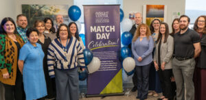Photo of our gme staff standing in front of a match day banner