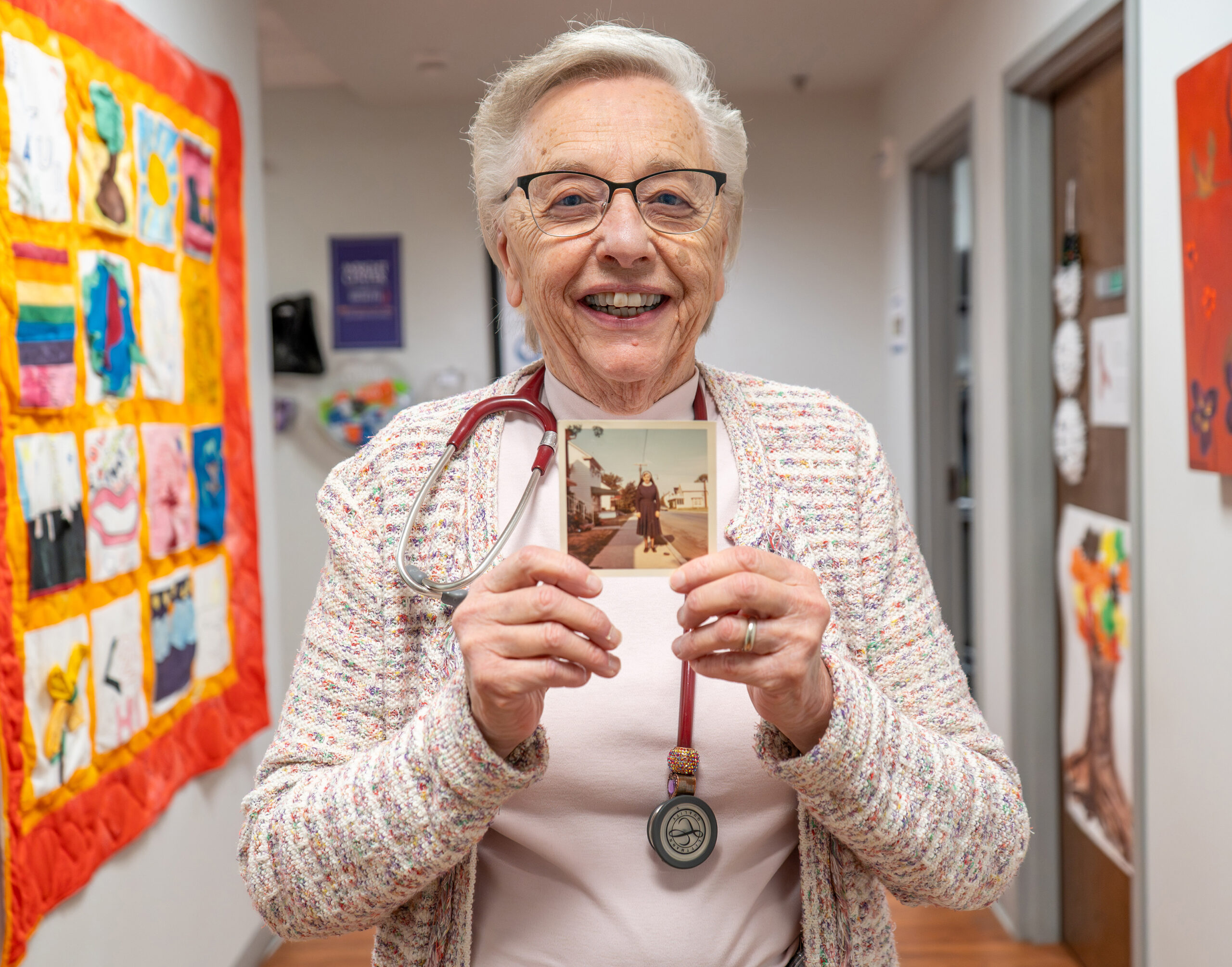 Sister Ruth Neely, a certified nurse practitioner at The Wright Center for Community Health’s Ryan White HIV/AIDS Clinic, holds a photo of herself in her habit in the late 1960s, just before she took her final vows for the Religious Sister of Mercy.