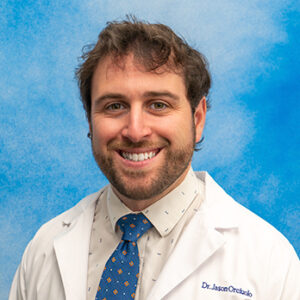 GI fellow Jason Orciuolo headshot in white coat and on blue background