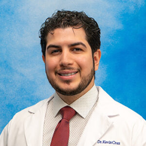 Cardio fellow Kevin Cruz-Lopez headshot in white coat and on blue background