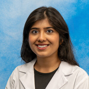 IM resident Tasneem Fatima headshot in white coat and on blue background