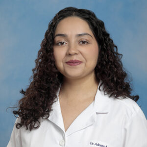 IM resident Adeena Azam headshot in white coat and on blue background