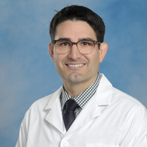 IM resident Elfego Galvan headshot in white coat and on blue background