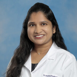 IM resident Harshini Reddy Yennam headshot in white coat on blue background