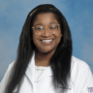 IM resident Maurielle Artis headshot in white coat and on blue background