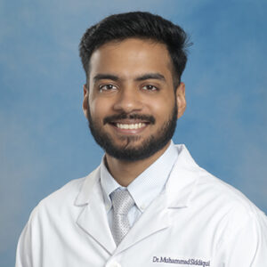 IM resident Muhammad Siddiqui headshot in white coat and on blue background