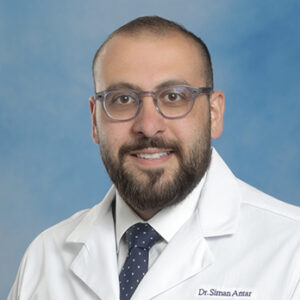 IM resident Siman Antar headshot in white coat and on blue background