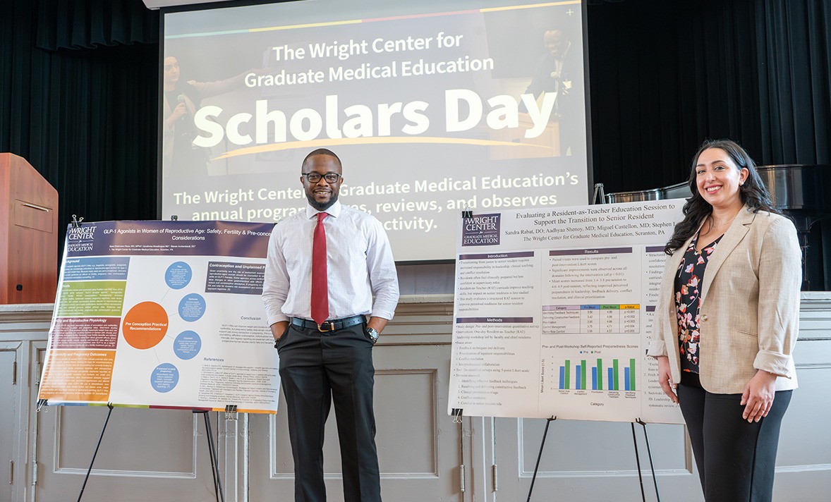 Two medical residents standing in front of their posters at Scholars Day May of 2026.